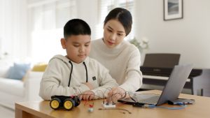 young student with their mother learning electronics