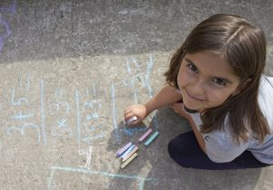 young girl doing math with chalk