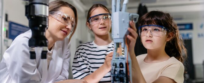 Teacher and girl students using hand robot